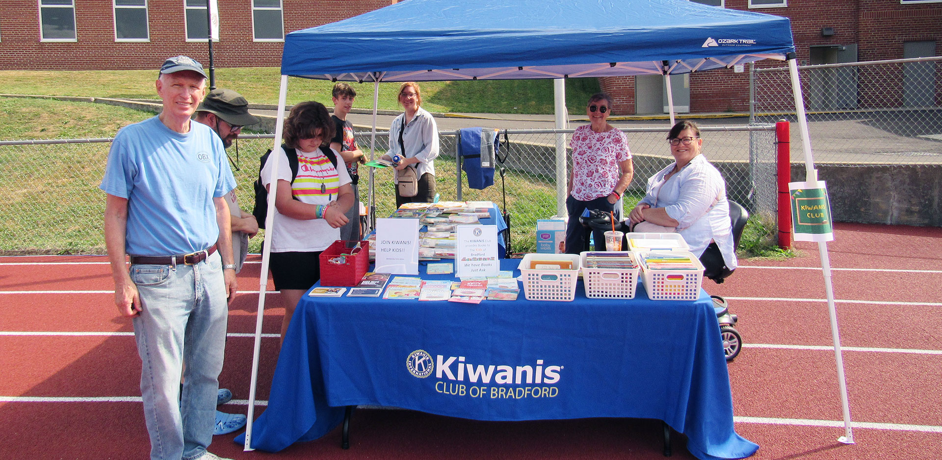 Dr. Dick Dryden Patricia Lanzon and Elyse and Liam Young working the Kiwanis Free Book table | Kiwanis Club of Bradford